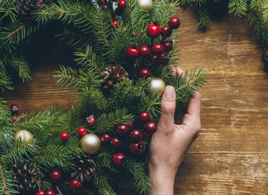 A person is holding a holiday wreath