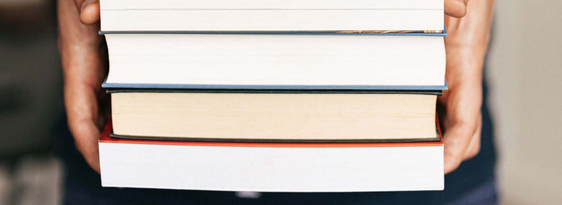 closeup of person holding pile of books