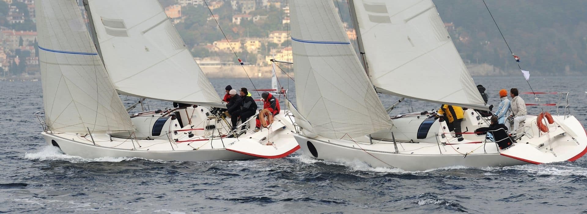 closeup of two teams in a sailboat race on the open water