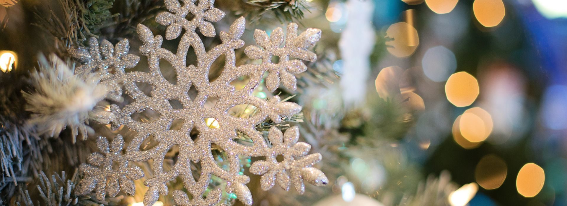 A silver glittered snowflake ornament on a Christmas tree