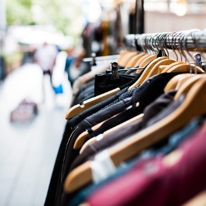 Clothing rack with brown wooden hangers on the outside of a street with blurred people in the background 