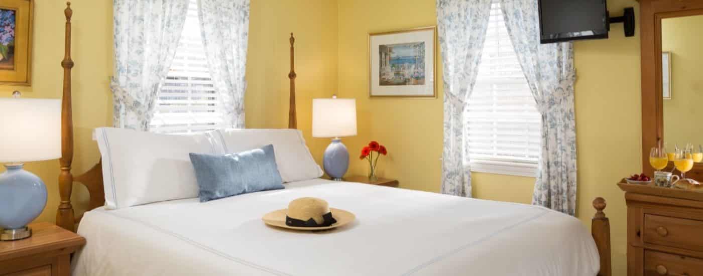 Bedroom with yellow walls, light wooden bed and dresser, white bedding, and flat-screen TV