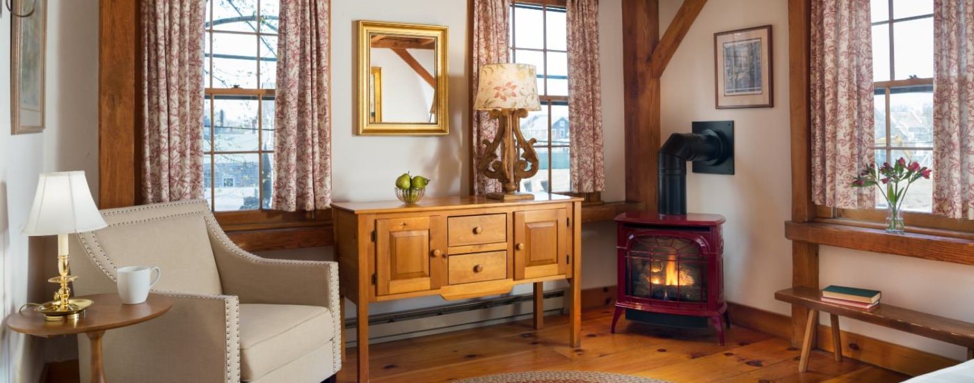 Bedroom with sitting area with upholstered arm chair, wooden buffet table, antique fireplace, and large area rug