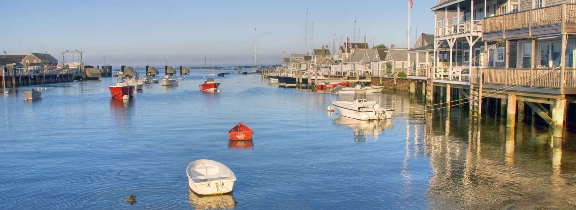 Many white and red small boats in calm blue water tied up to the wharf