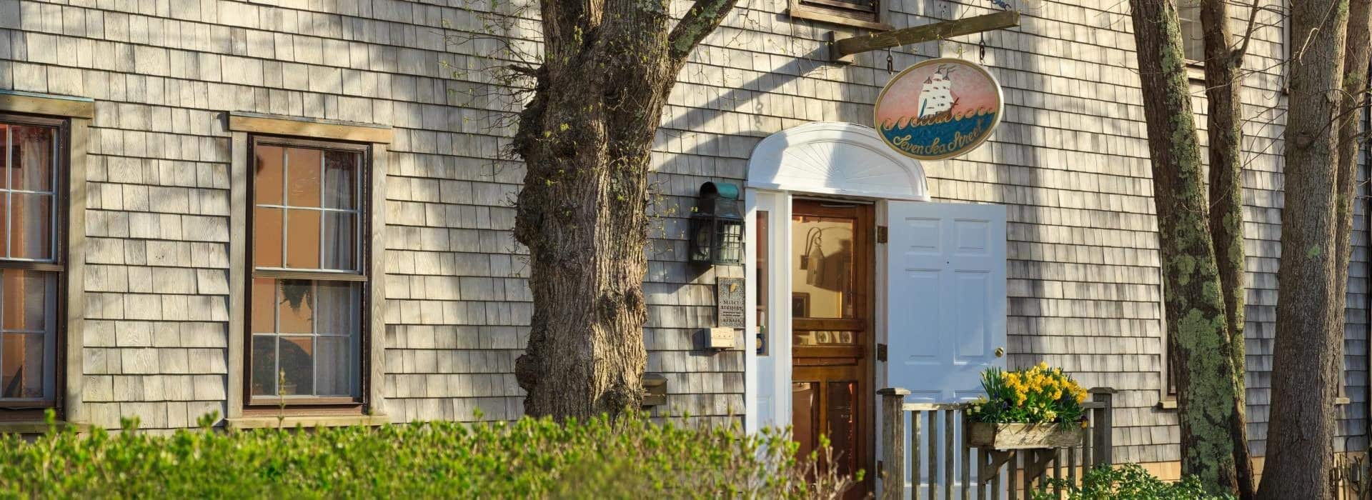 Front exterior view of the property with cedar shake siding, white painted door, and green shrubs