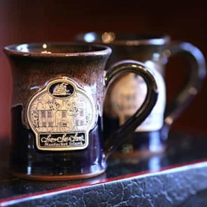 Dark colored stoneware mug with Seven Sea Street Inn logo on the front