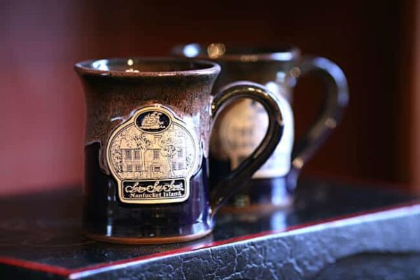 Dark colored stoneware mug with Seven Sea Street Inn logo on the front
