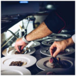 Two chefs adding touches to several white plates of food - image by fabrizio magoni unsplash.com